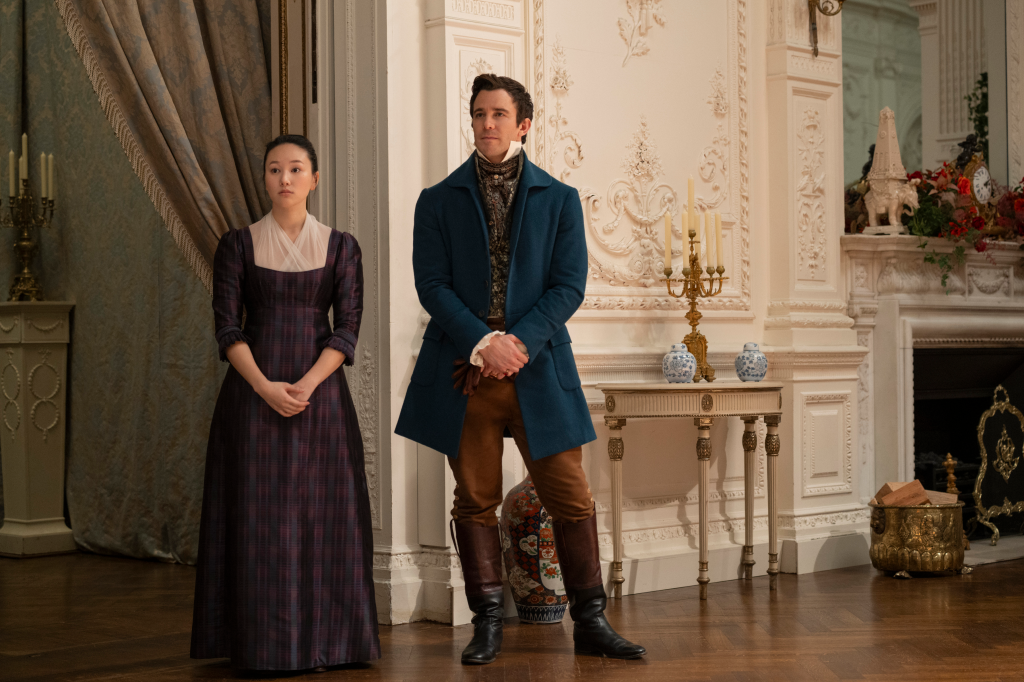 Yerin Ha as Sophie Baek and Luke Thompson as Benedict Bridgerton standing together in a grand room.
