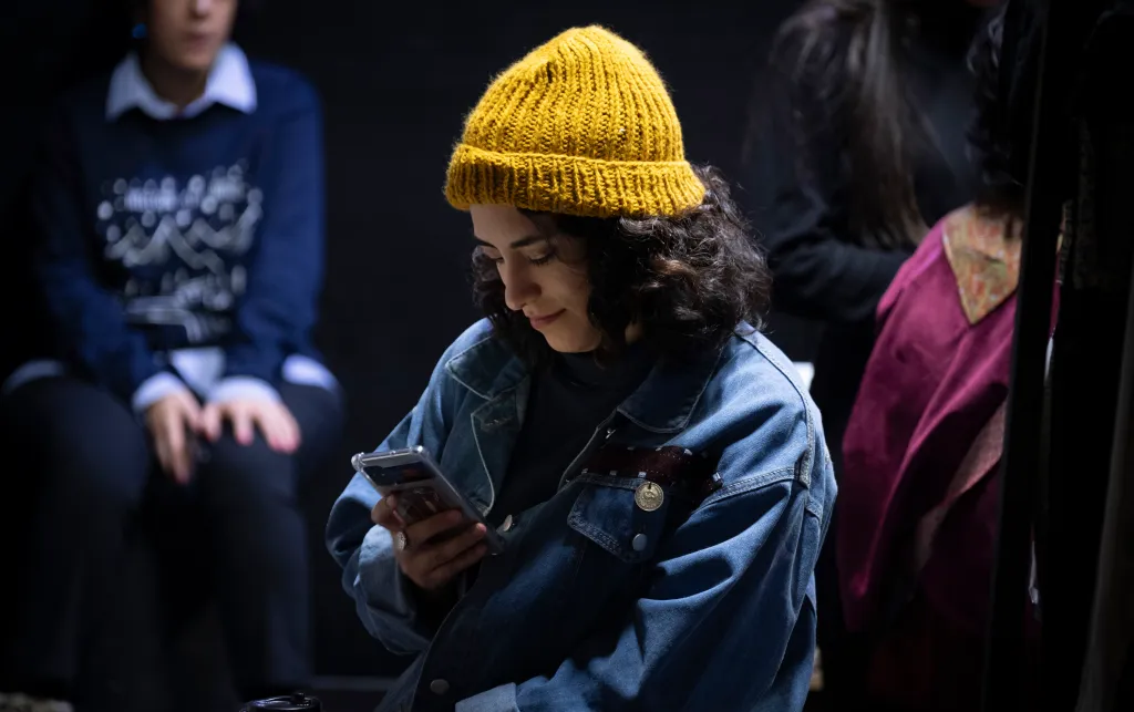 a person in a yellow winter hat looking at a phone