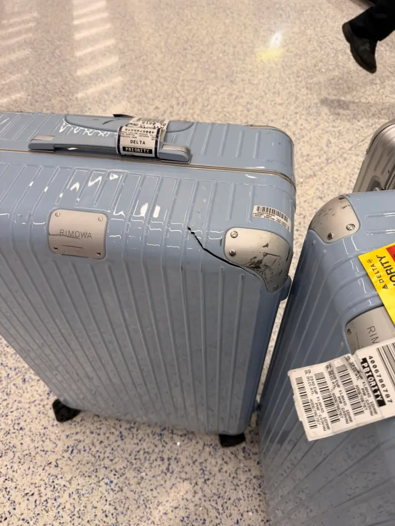 Two blue Rimowa suitcases with cracked corners and 