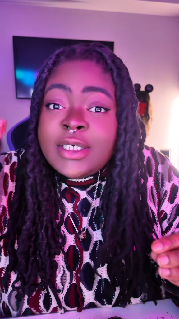 Chika in a selfie-style shot with pink lighting.