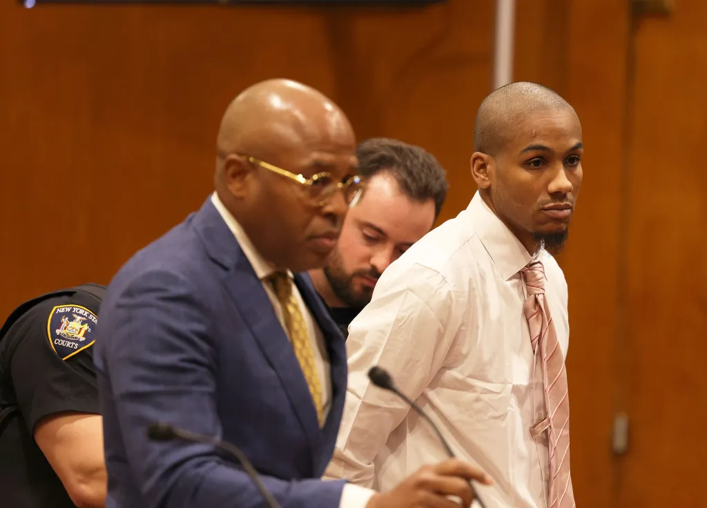 Man in gray suit and man wearing yellow shirt in court.