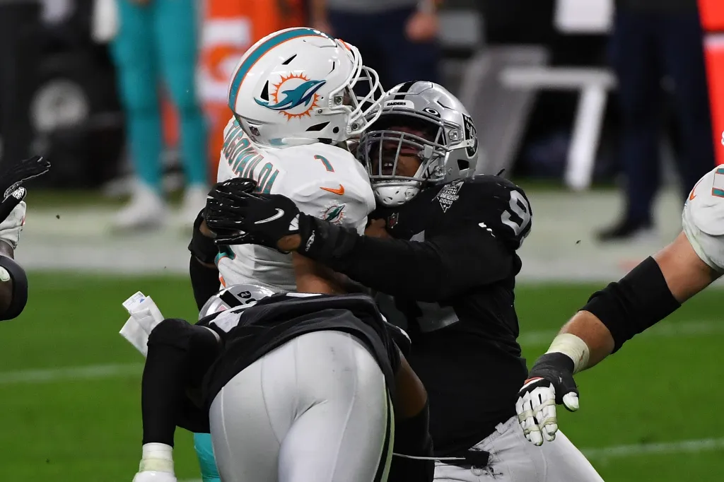 Tua Tagovailoa of the Miami Dolphins being sacked by Kendal Vickers of the Las Vegas Raiders.