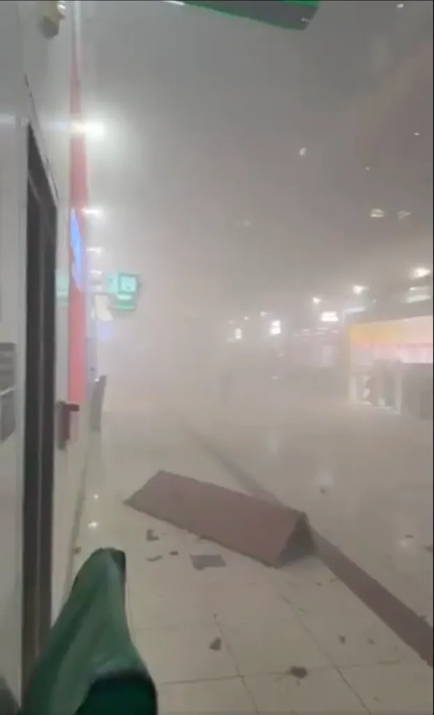 Indoor hallway filled with dust, possibly from an explosion or collapse, with debris on the floor.