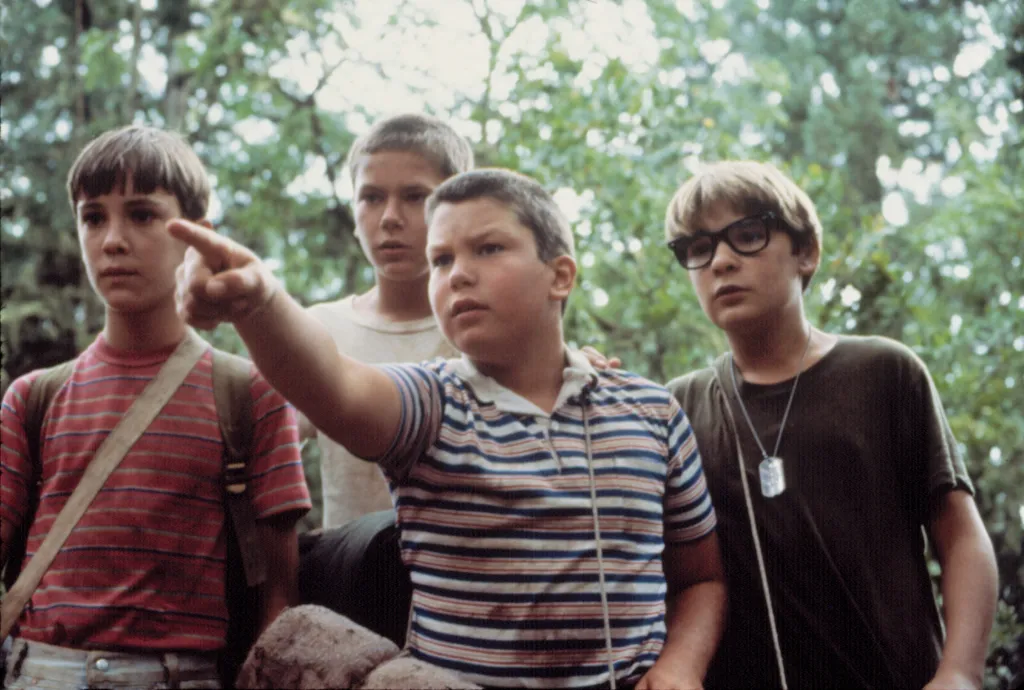 A boy in a striped shirt pointing, surrounded by three other boys.