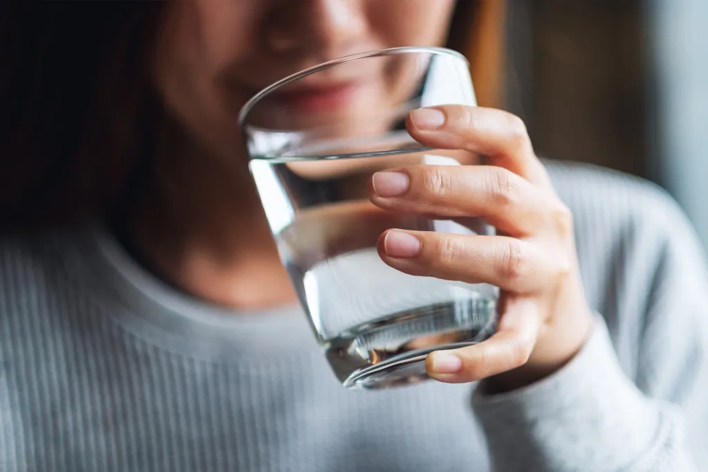 A person holding a glass of water to their mouth.