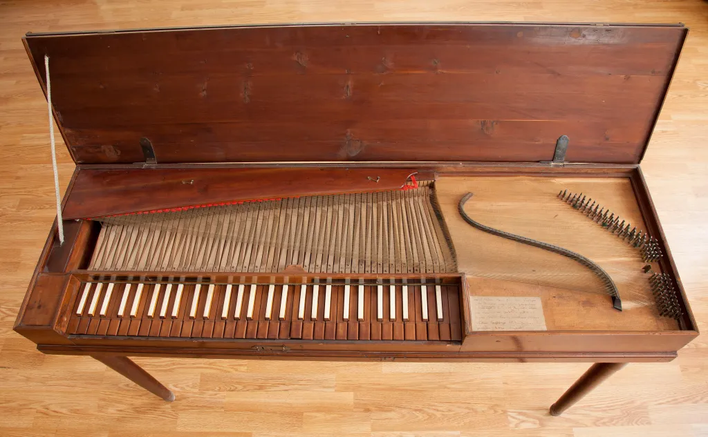A clavichord with its lid open, exposing the keys, strings, and internal mechanisms.