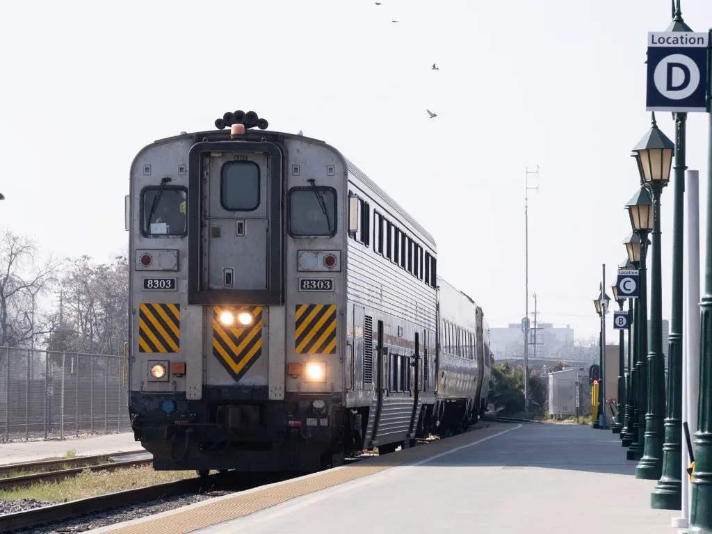 An Amtrak train with its lights on, sitting at the Bakersfield Train Station.