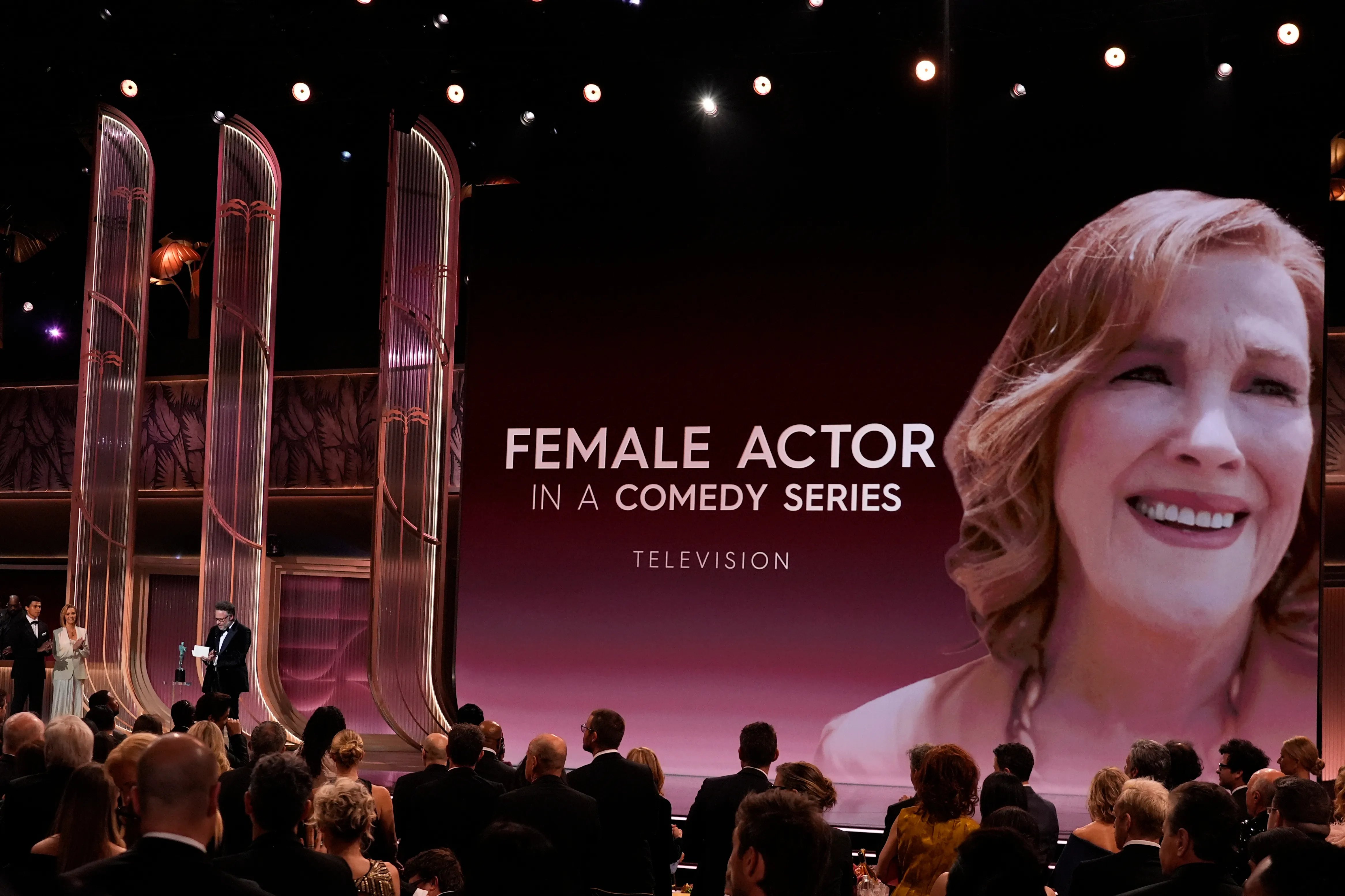 Seth Rogen accepts the award for Outstanding Performance by a Female Actor in a Comedy Series on behalf of Catherine O'Hara while Lisa Kudrow looks on.
