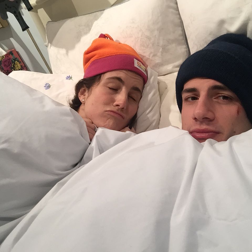Jack Schlossberg and Tatiana Schlossberg lying in bed, both wearing beanies.