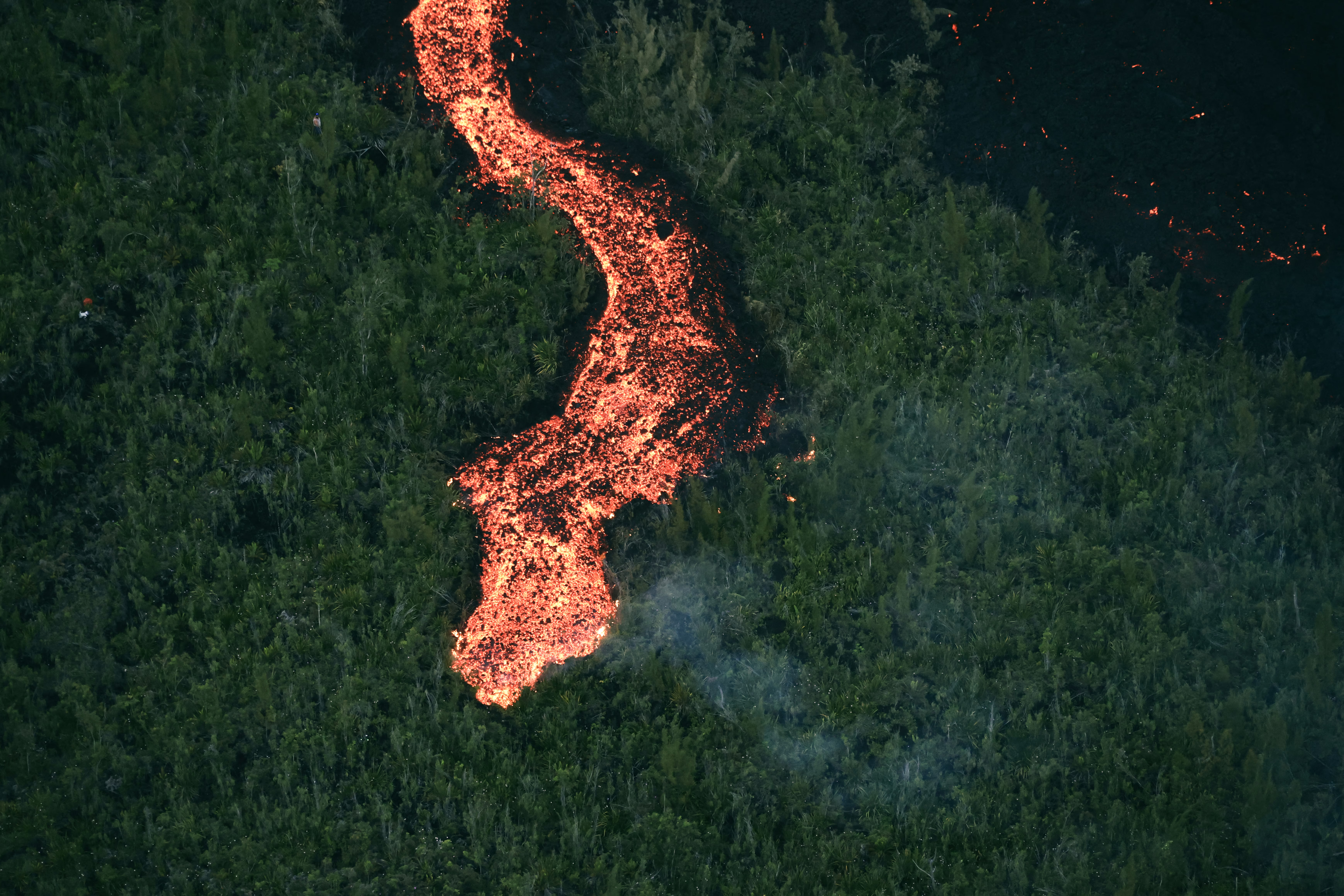 An aerial image of a lava flow making its way through a forested area