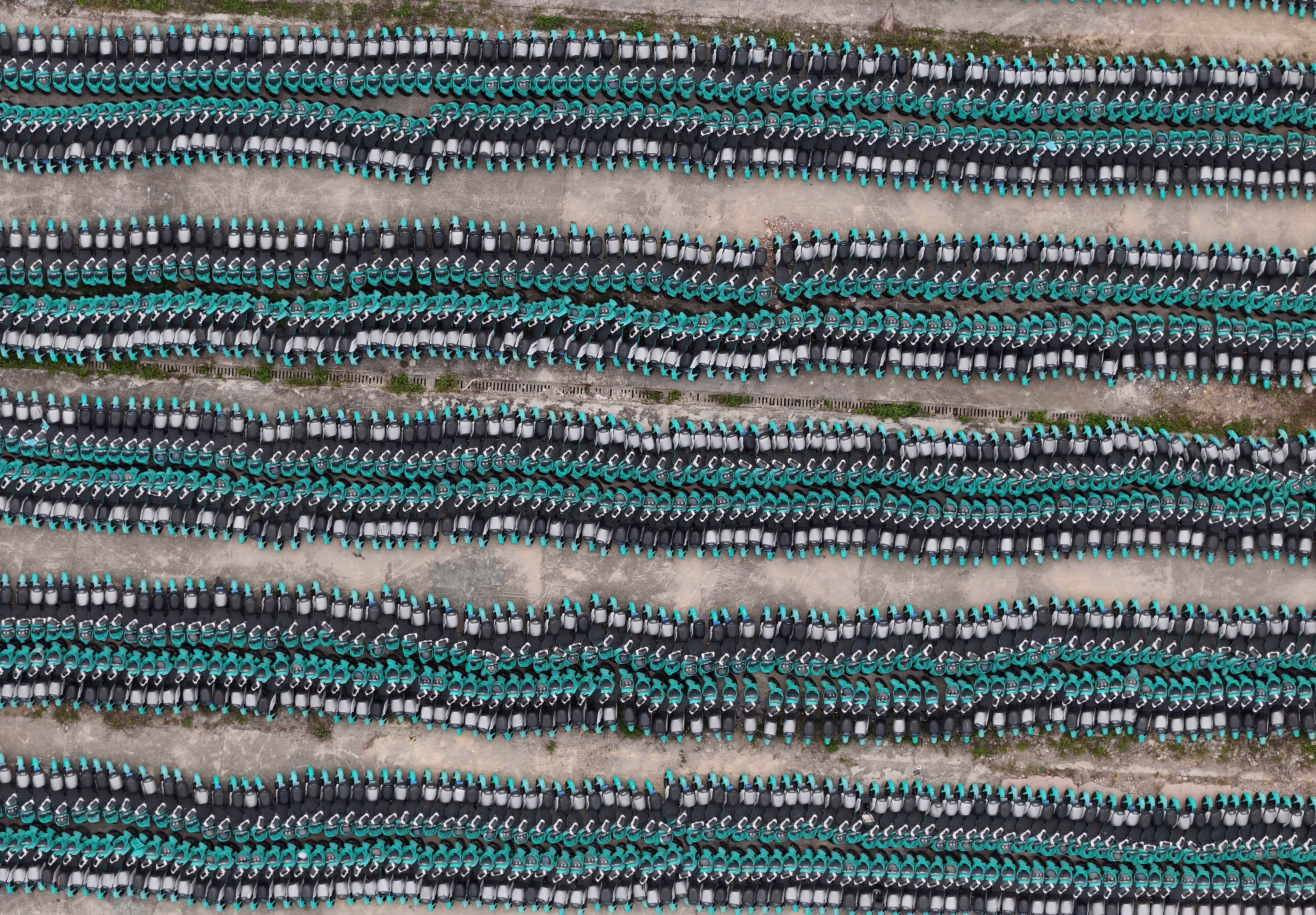 Long densely-packed rows of unused shared electric bicycles, seen from above