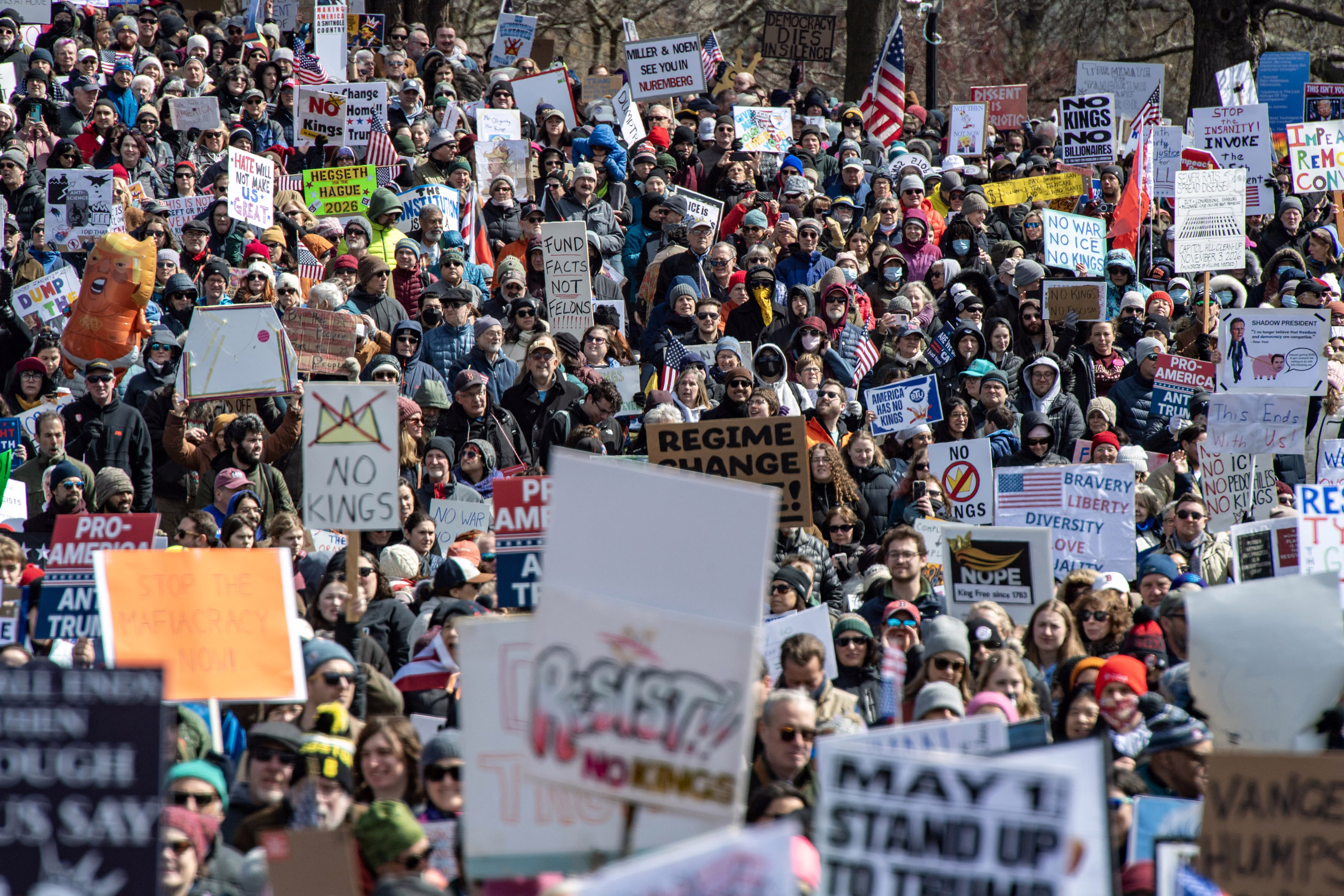 A large crowd of protesters, most holding American flags or anti-Trump signs