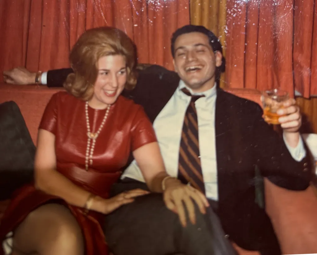 Barbara Waldman and a man laughing on a red couch.