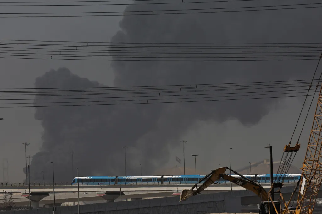 A metro train passes a smoke cloud rising from the port of Jebel Ali in Dubai after an Iranian airstrike.
