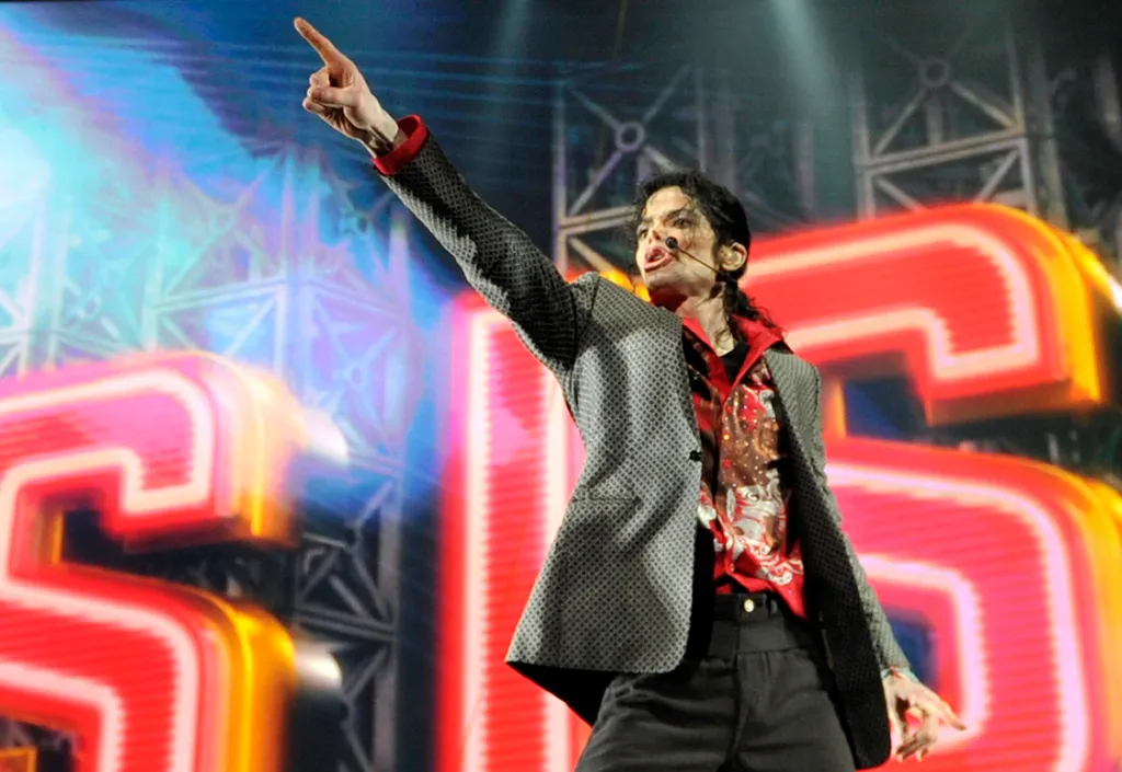 Michael Jackson on stage, pointing skyward during a performance.