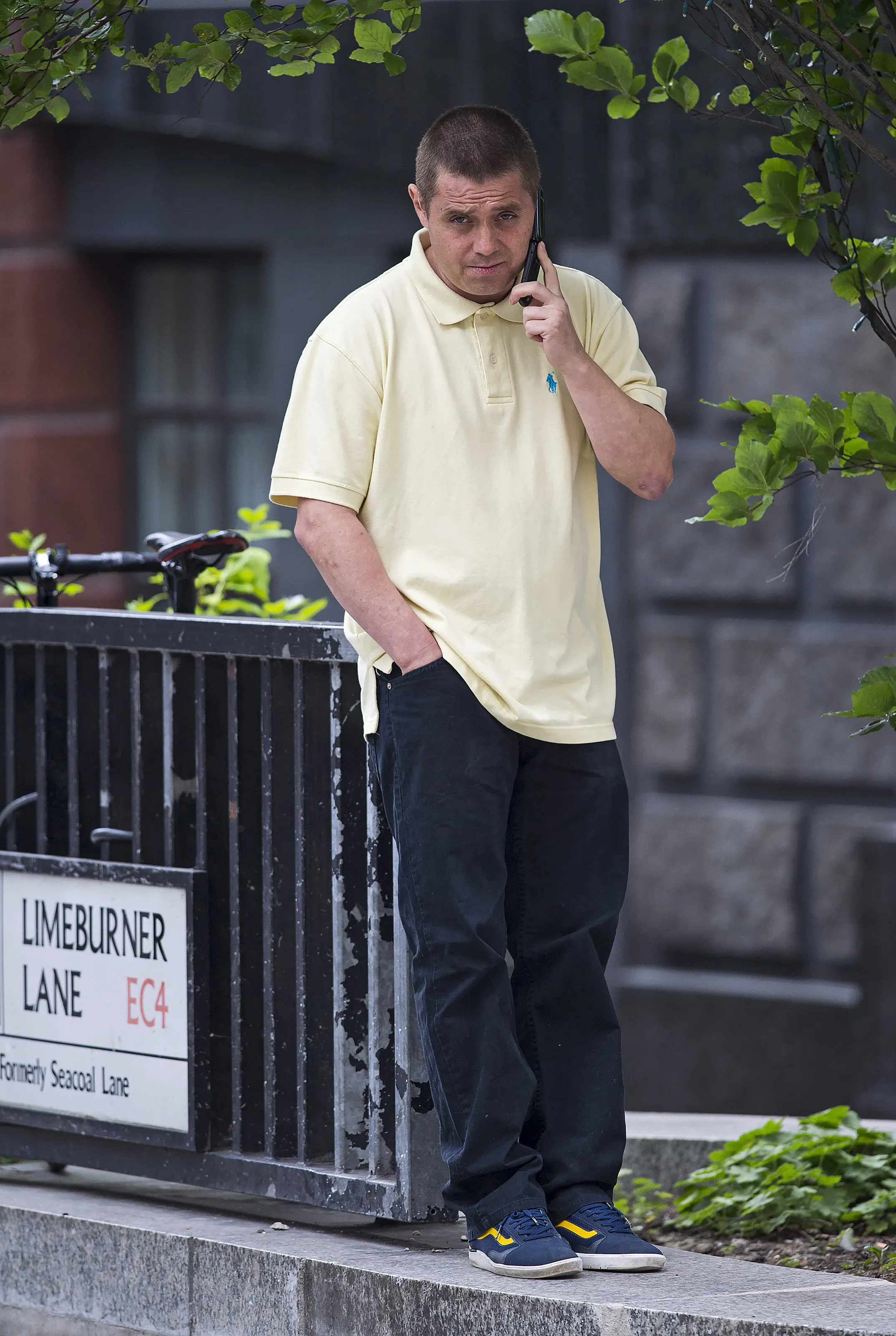 Actor John Alford talking on the phone while standing on the street.