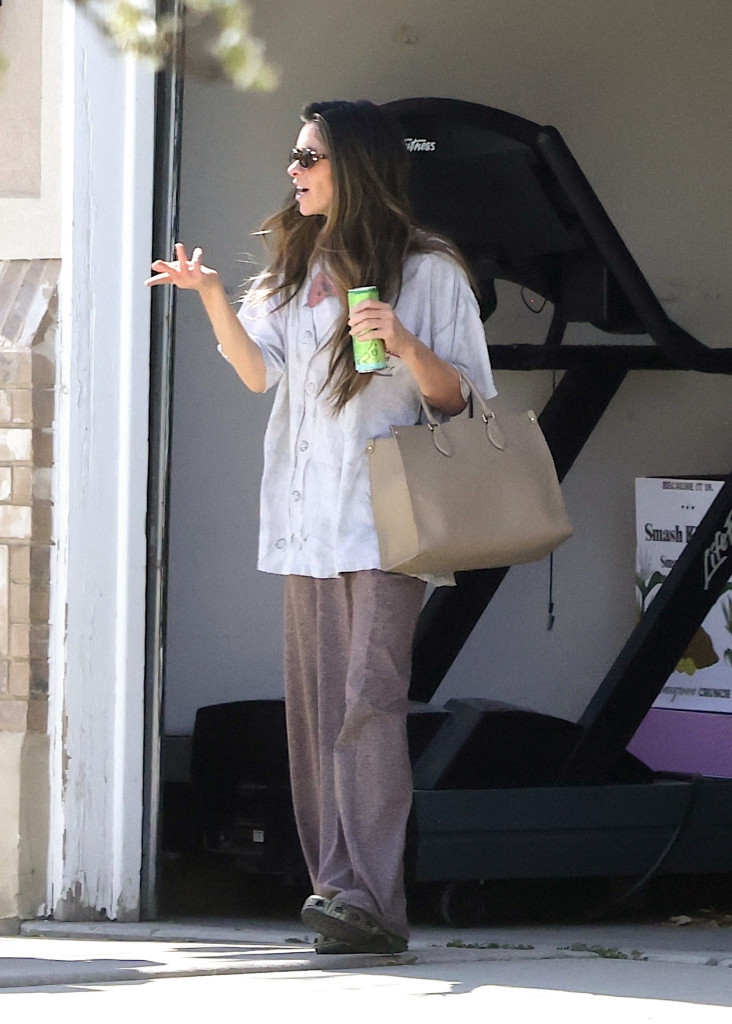 Taylor Frankie Paul, holding a green drink and a beige handbag, speaks to someone off-camera.