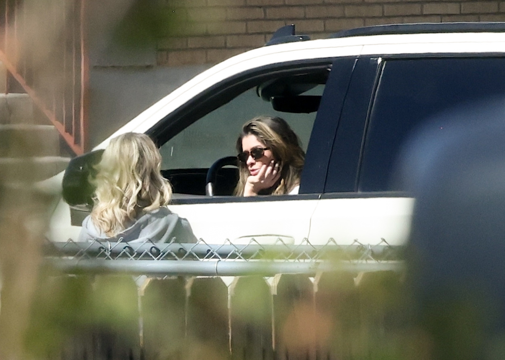Taylor Frankie Paul in sunglasses, resting her chin on her hand, in the driver's seat of a white SUV, talking to a blonde woman outside the car.