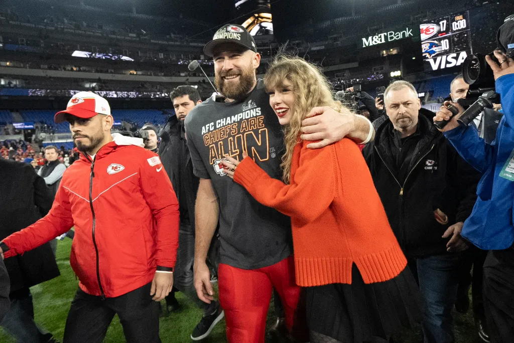 Travis Kelce and Taylor Swift walk together after the AFC Championship football game.