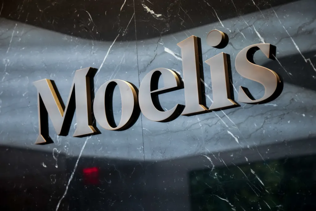 Moelis & Co. signage on a dark marble wall.