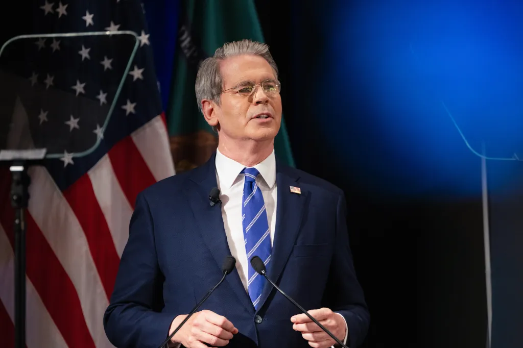 Scott Bessent, US Treasury Secretary, speaking at an event with the American flag in the background.