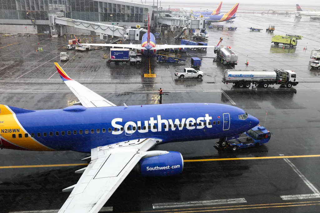 A Southwest Airlines Boeing 737 aircraft on a wet tarmac in the snow at LaGuardia Airport.