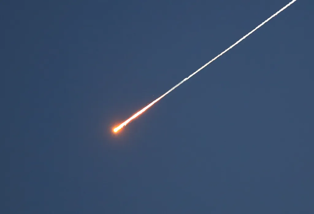 Missile launched from Yemen toward Israel, visible as a bright orange streak with a white smoke trail against a dark blue sky.