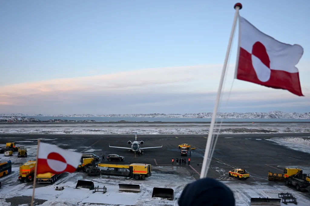 Greenlandic flag with an airport and snowy mountains in the background.