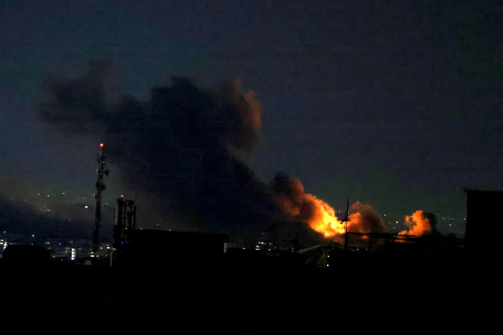 A plume of smoke rising from a strike in Tehran against a night sky.
