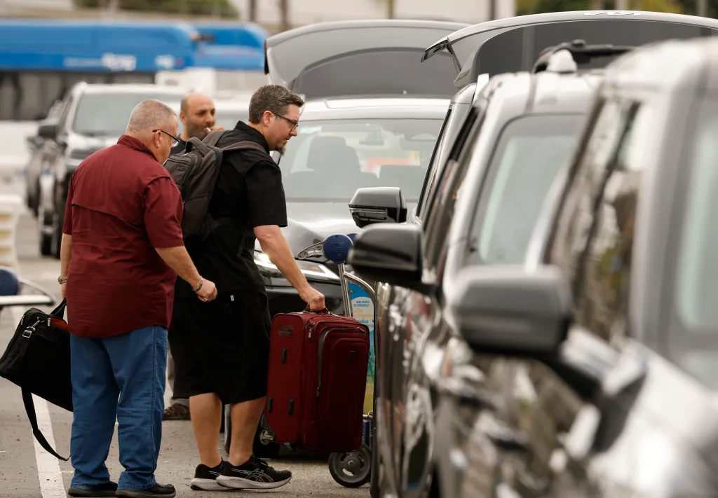 A traveler loads his luggage into a rideshare car at the LAX-it rideshare pickup location.
