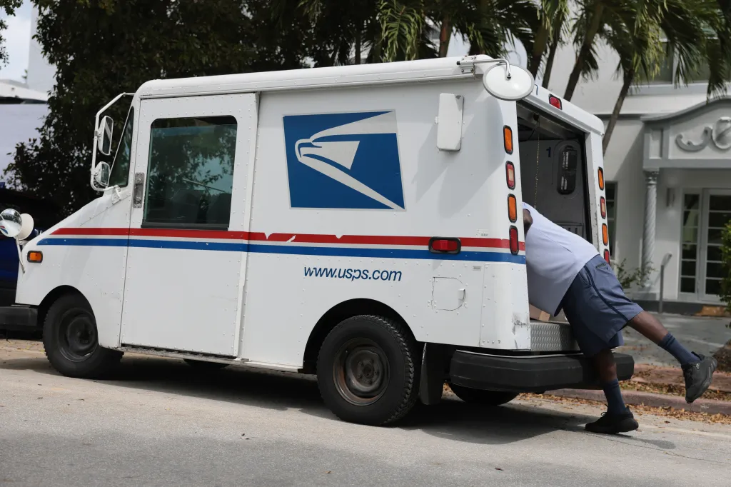 Postal carrier Marc Jacques loading mail into a USPS truck.
