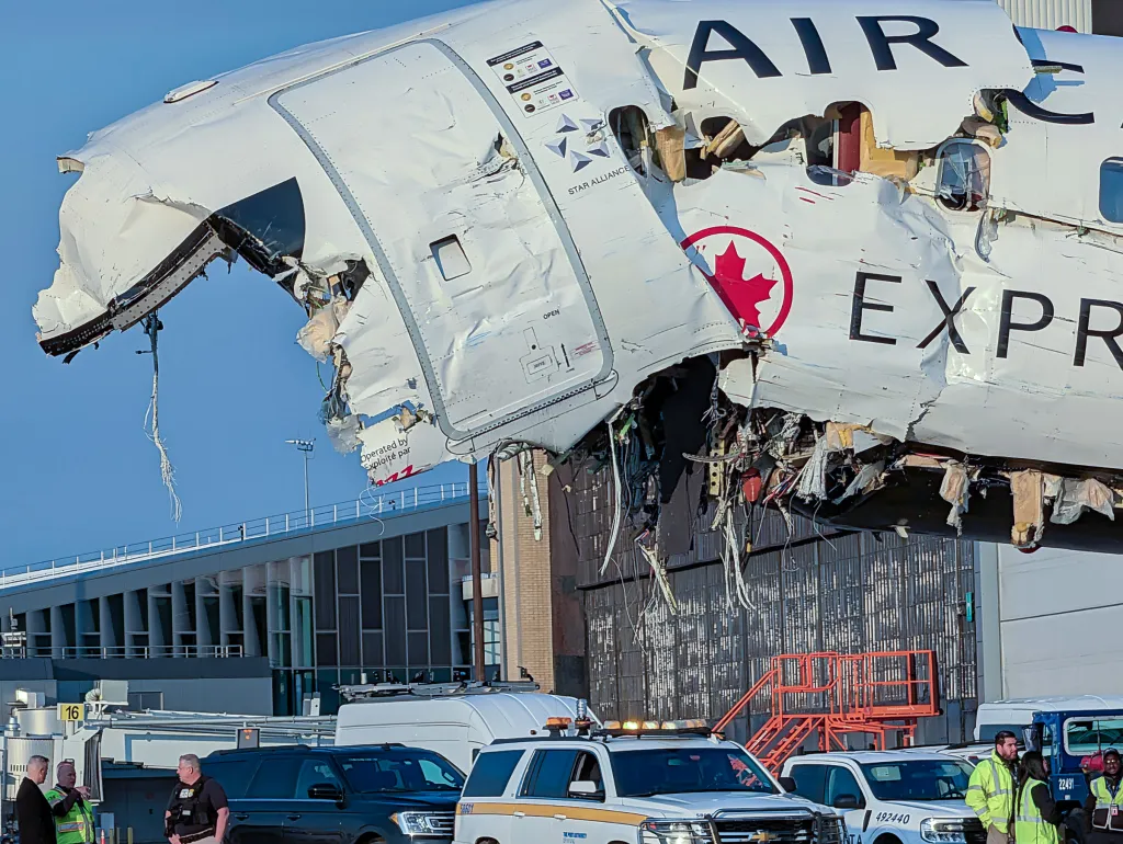 Damaged Air Canada plane in a hanger being unloaded of passenger belongings.