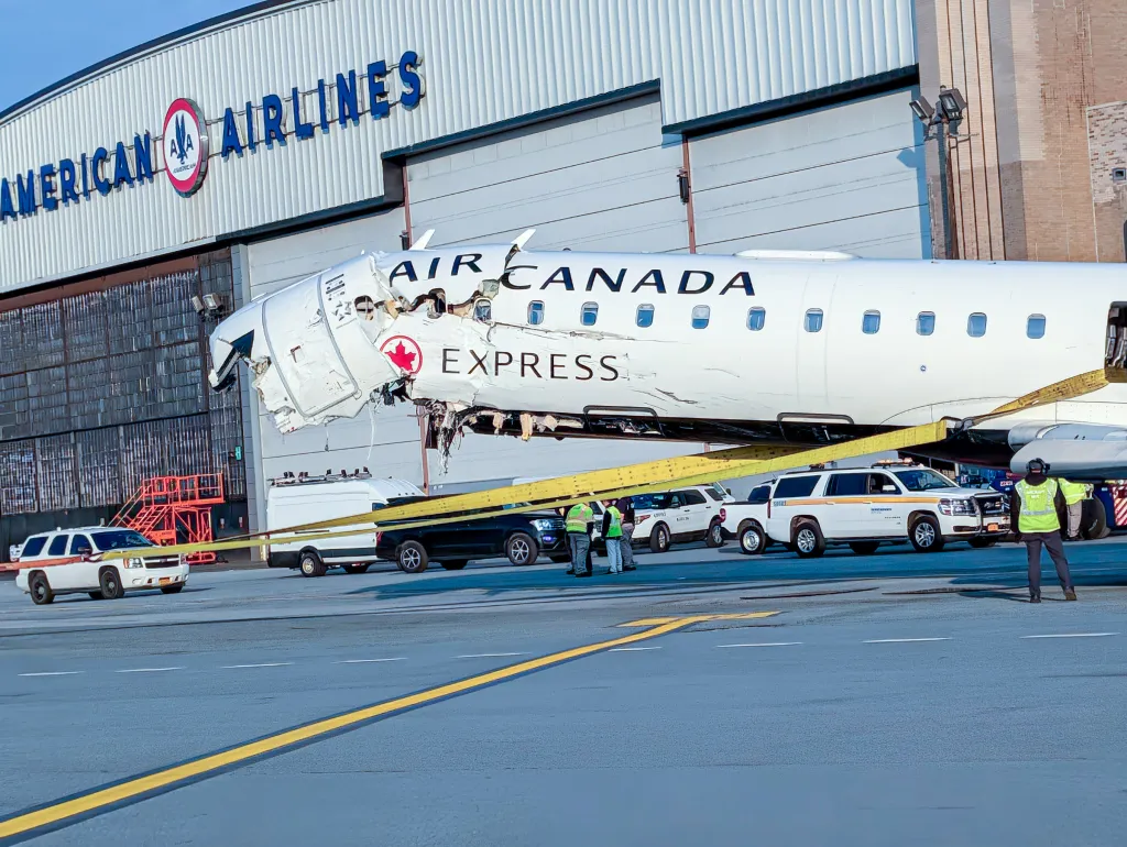 Damaged Air Canada Express plane moved to an American Airlines hangar to unload passenger belongings.