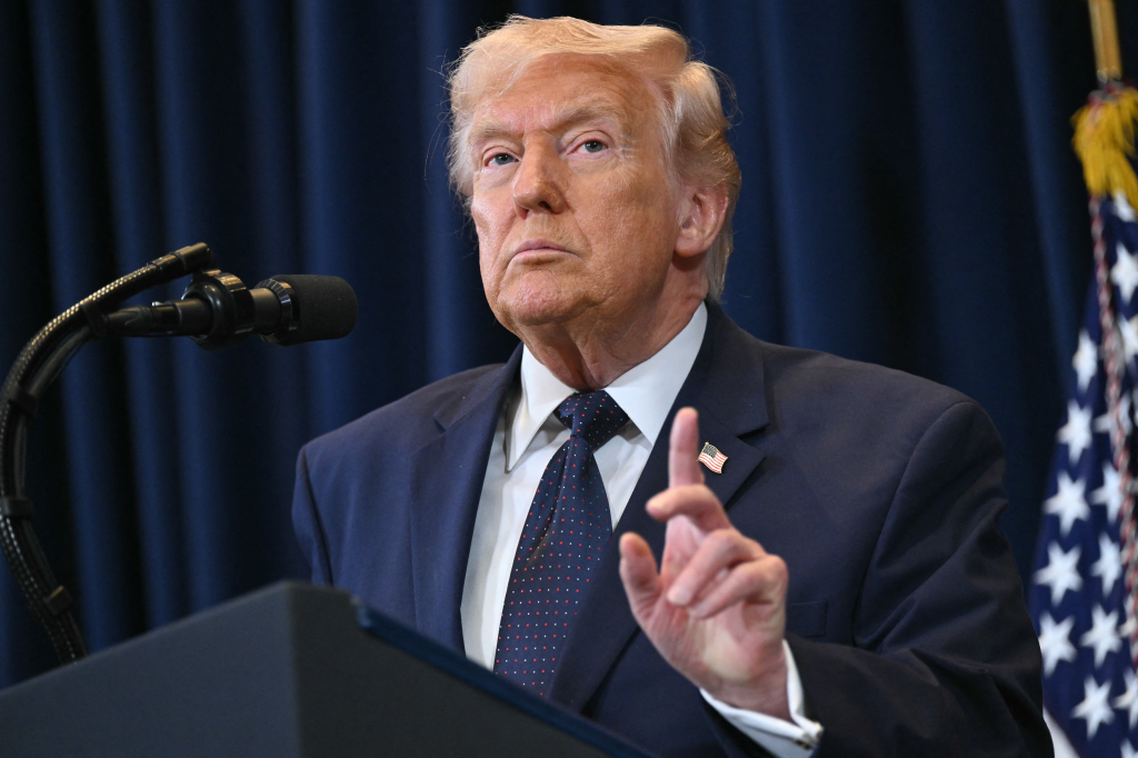 US President Donald Trump speaks at a press conference, gesturing with his hand.