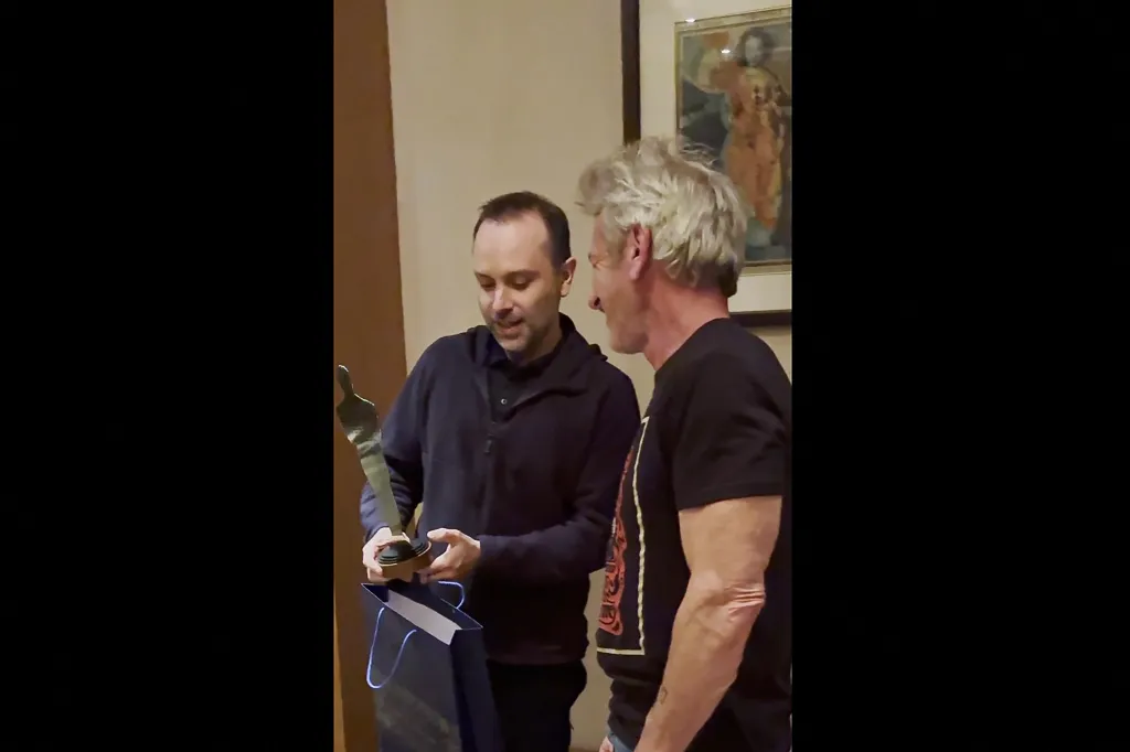 Sean Penn receiving a statuette made from damaged train carriage metal in Kyiv.