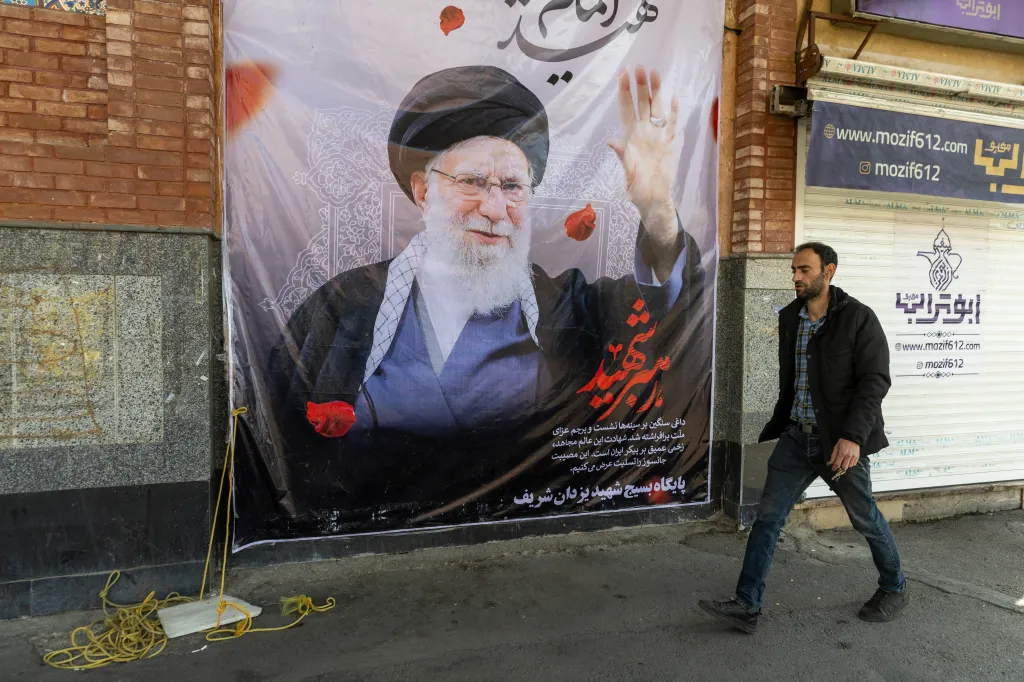 A man walks past a large poster of Ayatollah Ali Khamenei on a building in Tehran, Iran.