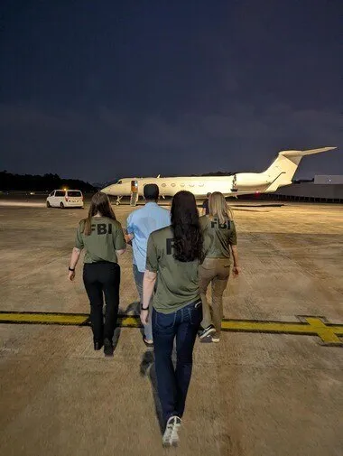 FBI agents escort Zobaidul Amin to an airplane.