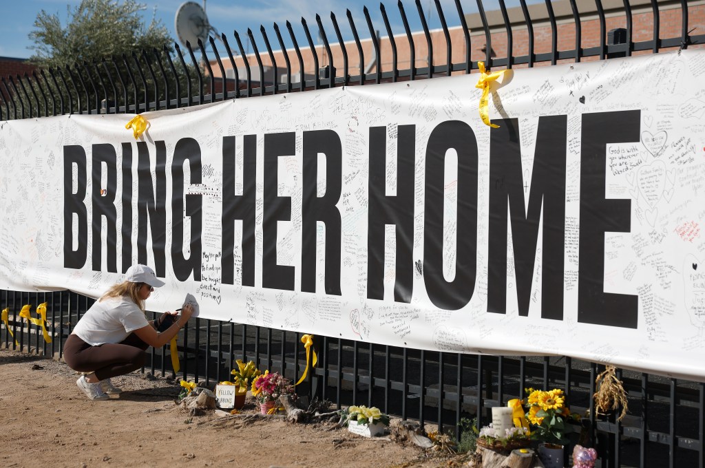 A woman writing on a large white banner that reads