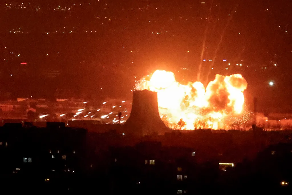 Explosion with large bright orange flames next to Azadi Tower at night.