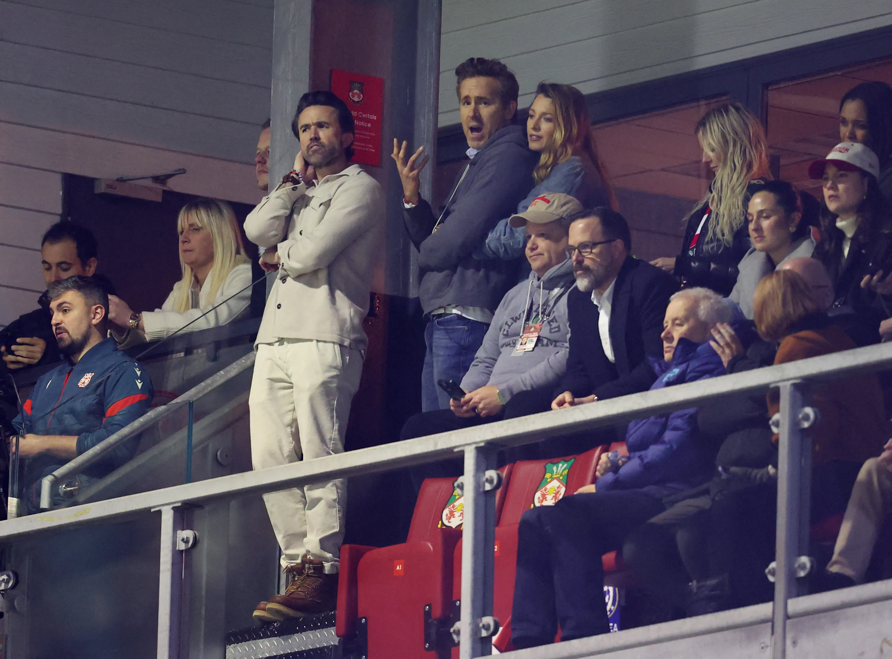 Ryan Reynolds, Blake Lively, and Rob McElhenney among other spectators at a Wrexham AFC football match.