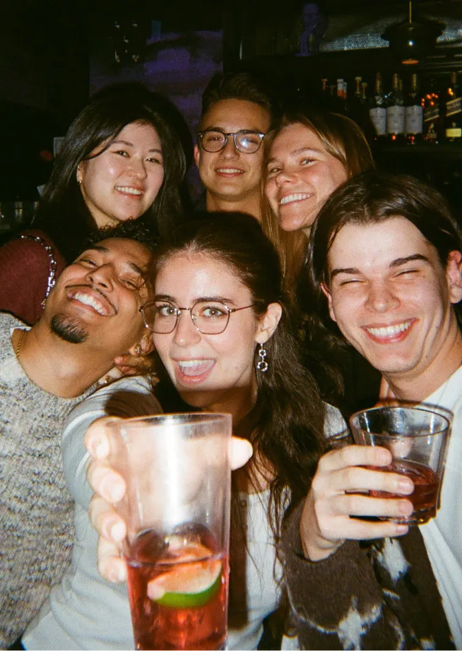 Six friends smiling at a meetup with drinks.