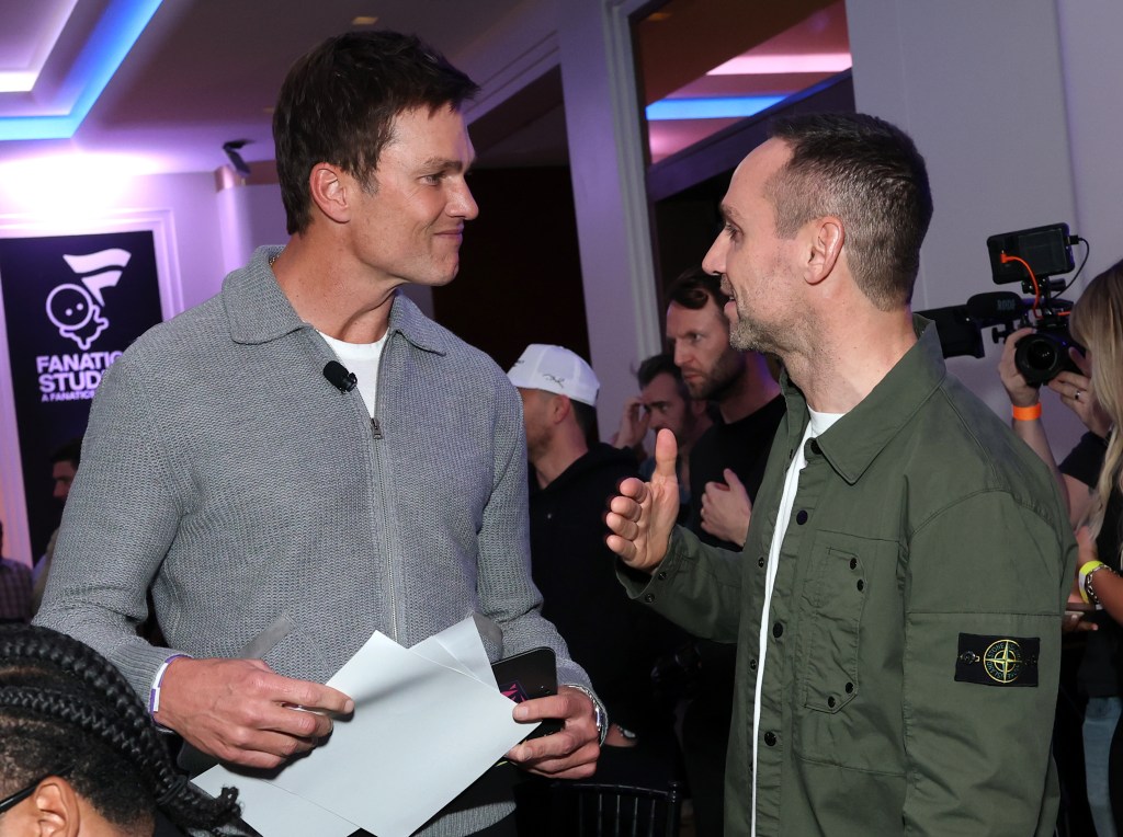 Tom Brady conversing with another man at the Fanatics Flag Football Classic Draft.