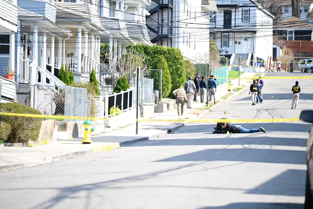 FBI Evidence Response Team agents and police work at a crime scene on a residential street.