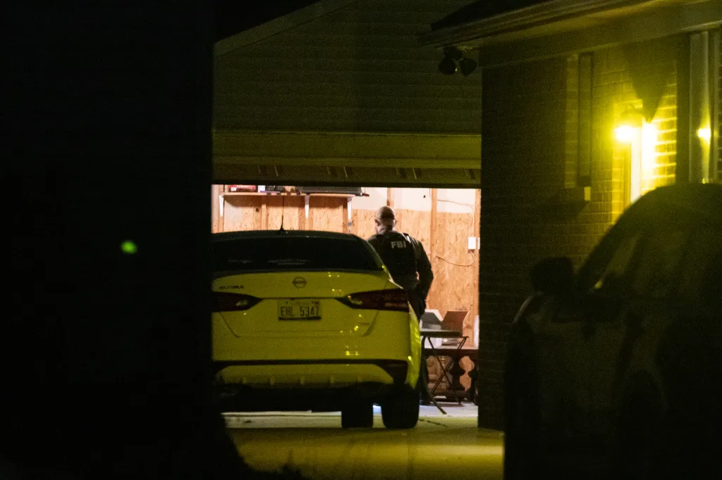 FBI agent standing in an open garage next to a car.