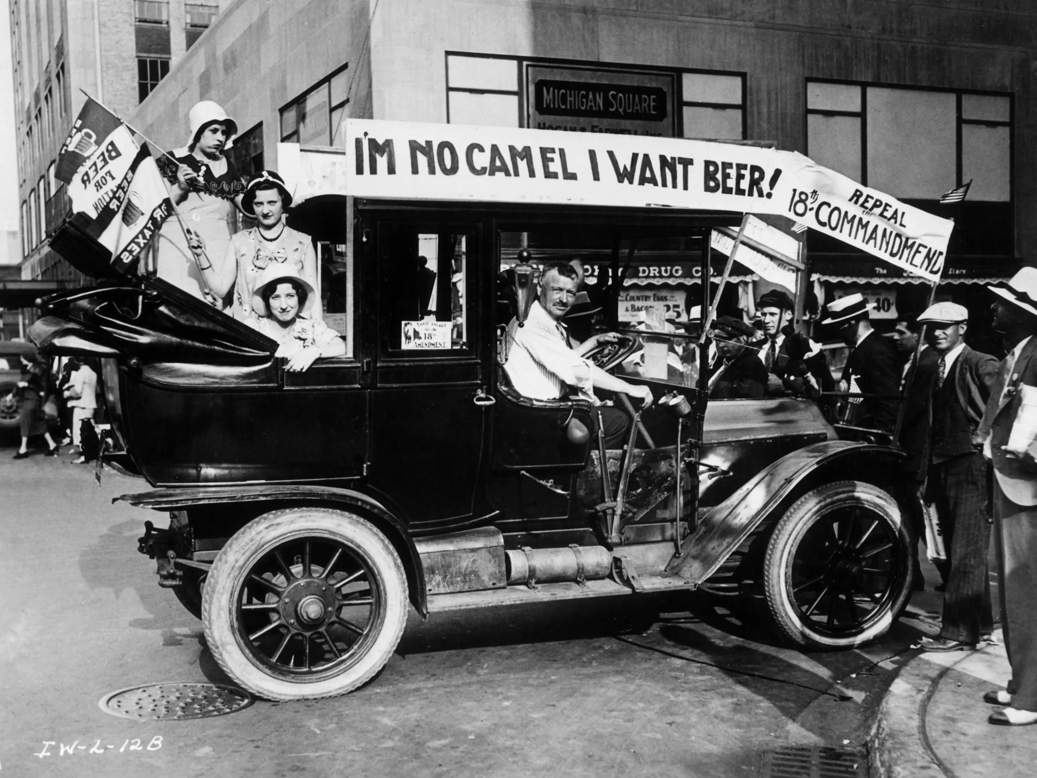 A group of people in a car protesting Prohibition. The car is decorated with a sign that reads, 