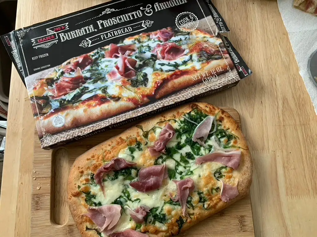 Trader Joe's burrata and prosciutto flatbread on cutting board beside regular box