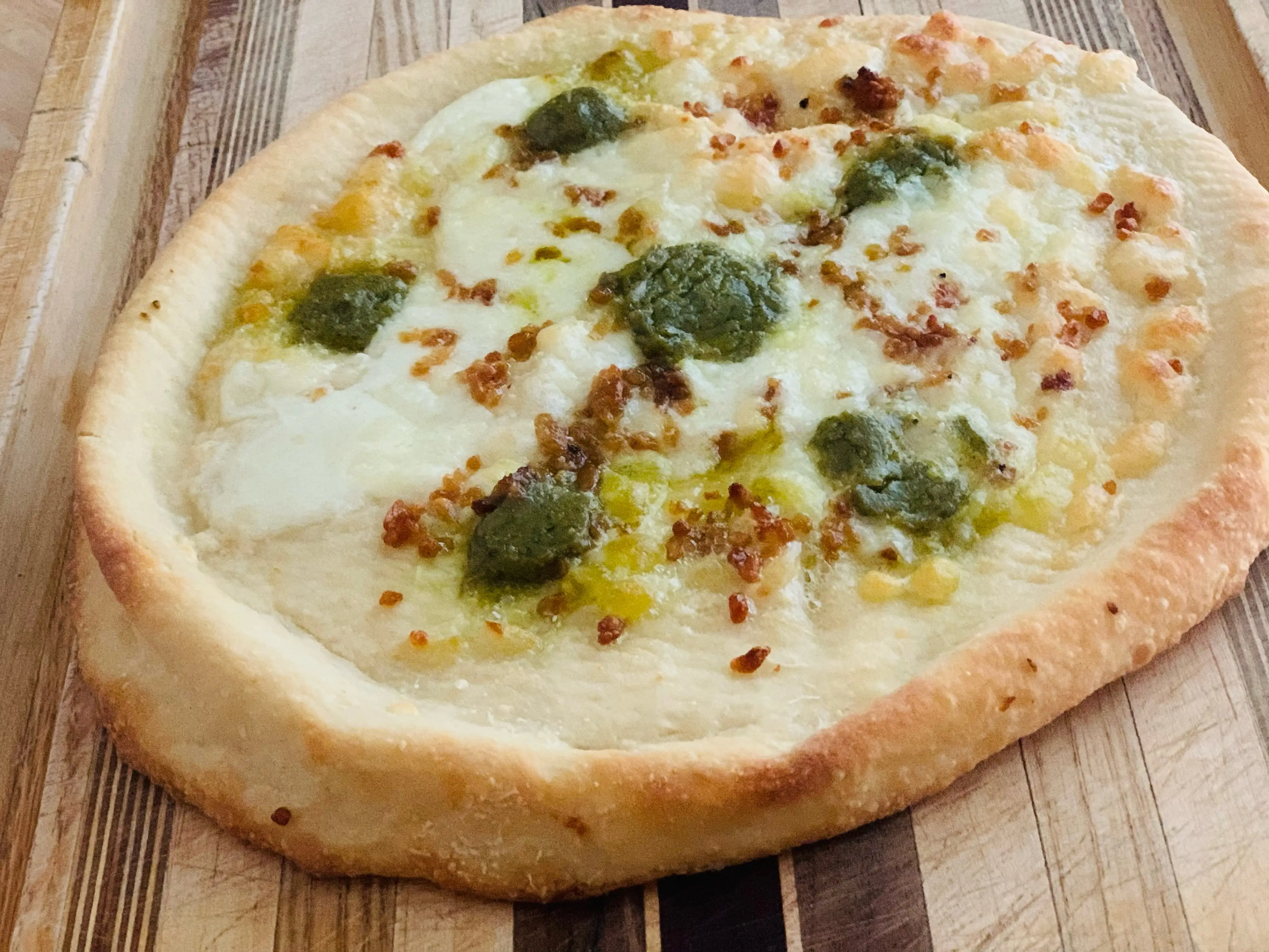 cooked Trader Joe's garlic pesto pizza on wooden cutting board