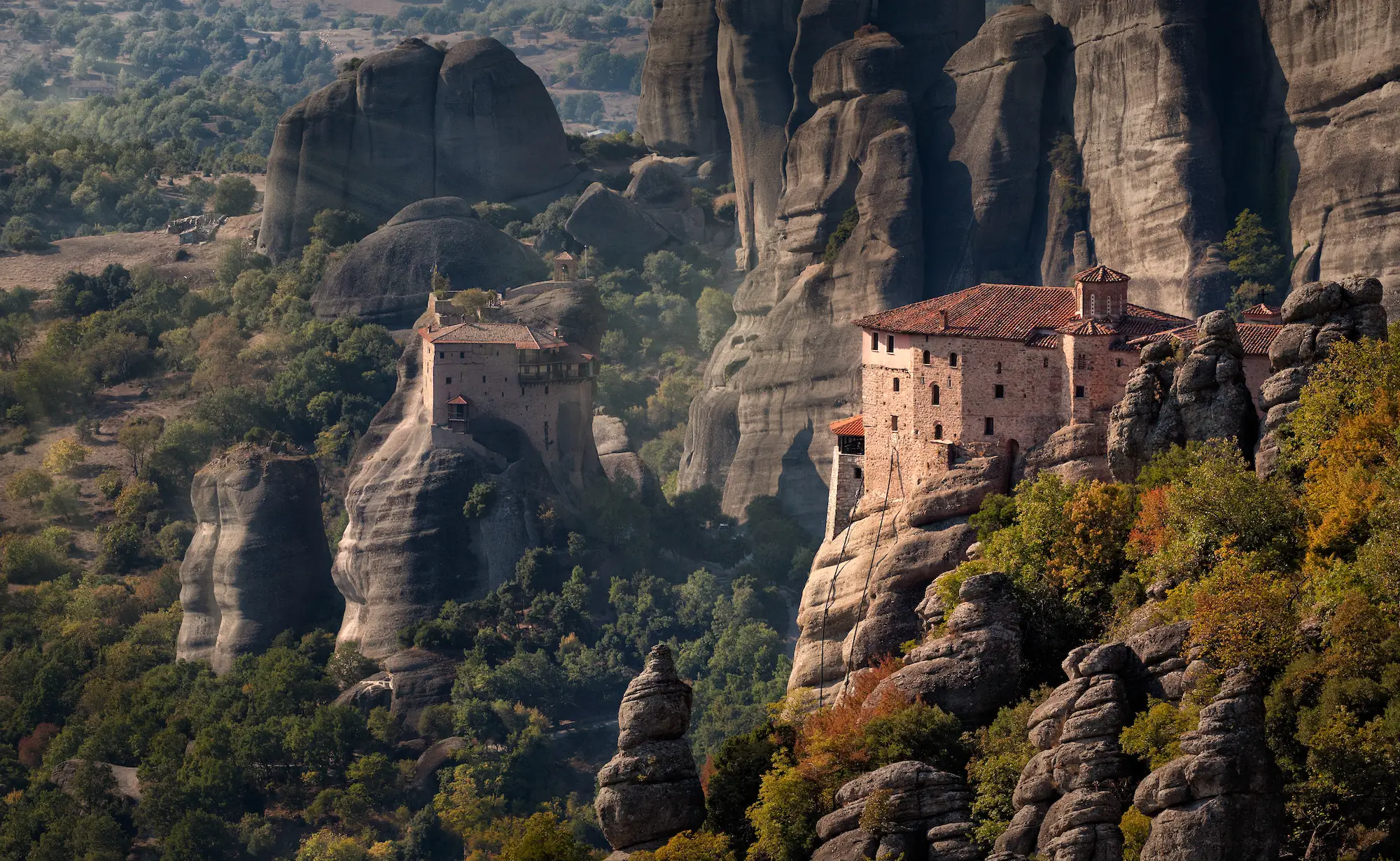 Monastery buildings on rock formations in mountains.