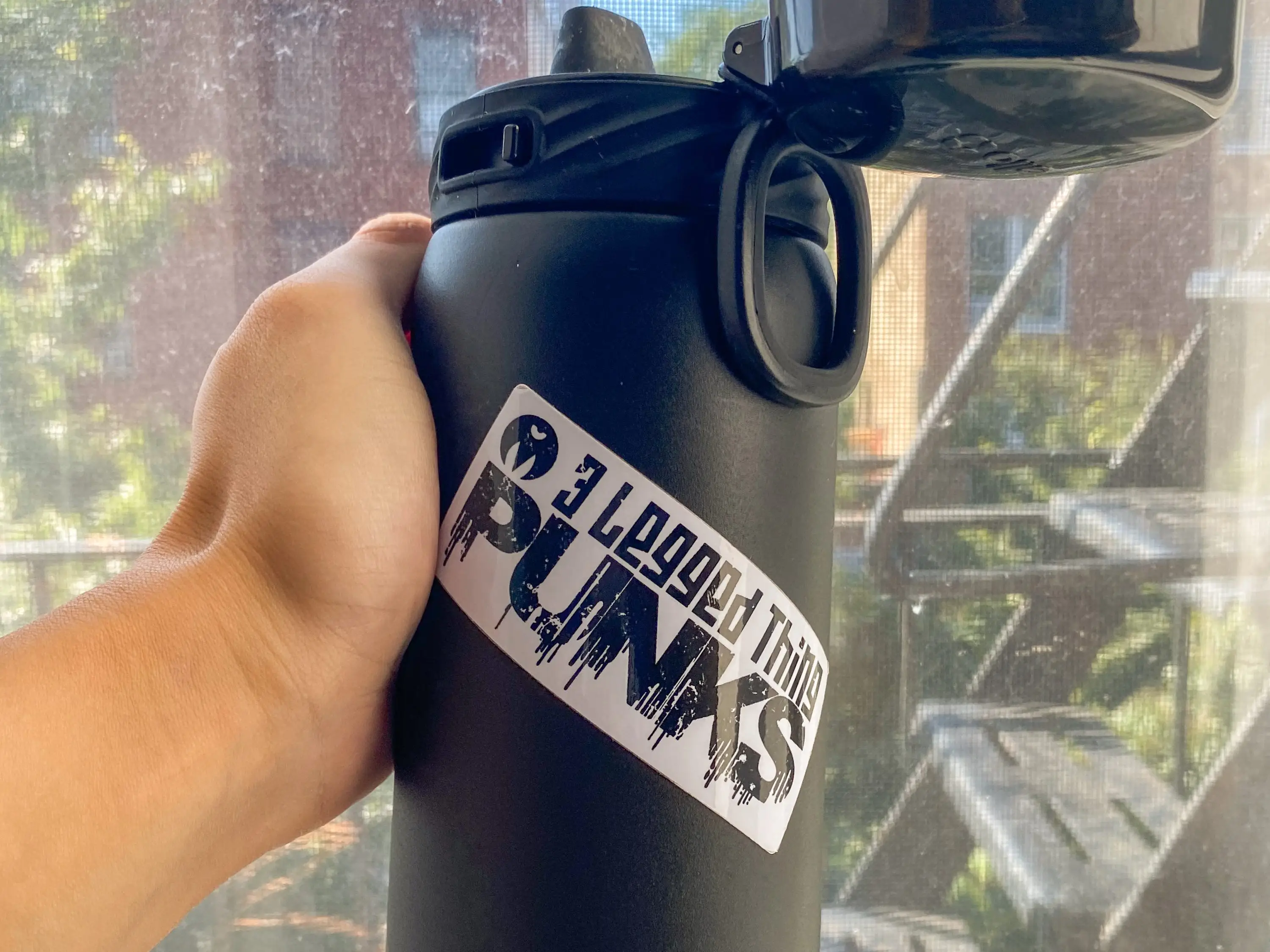 A hand holding a water bottle with a sticker on it