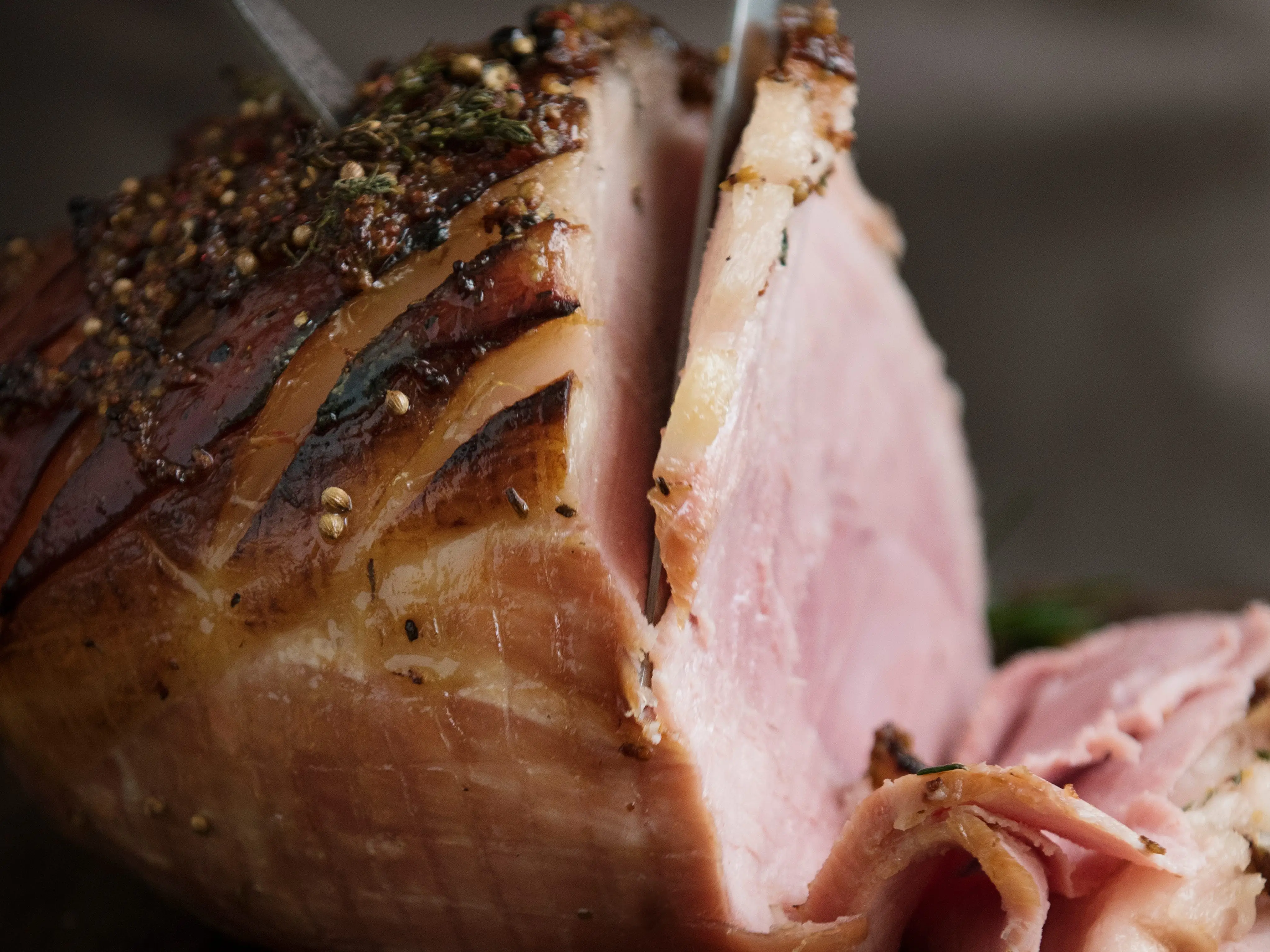 A knife slicing into ham